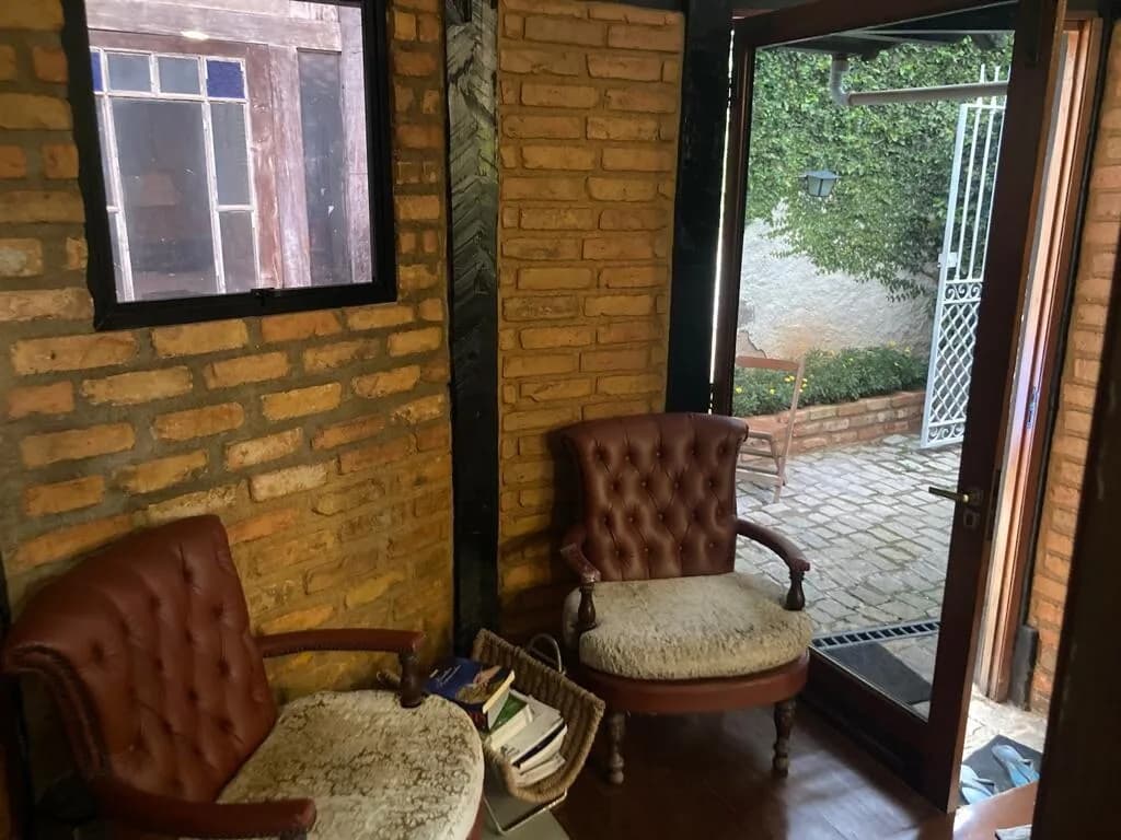 Loft Cozy House: Poltronas de couro, tijolo aparente e porta de vidro que abre para o jardim.